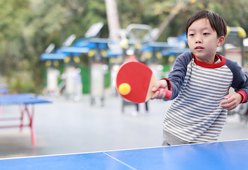 Smiling boy playing table tennis in garden