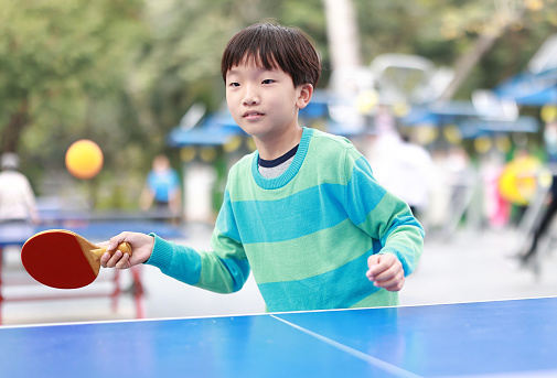 Smiling boy playing table tennis in garden