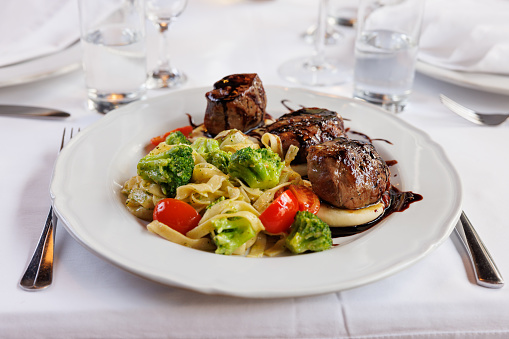 Beef chops on goat cheese seasoned with balsamico, served with tagliattele and vegetables