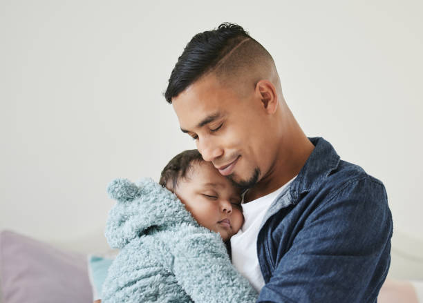 Shot of a young father embracing his baby at home I'll protect you forever father and baby stock pictures, royalty-free photos & images