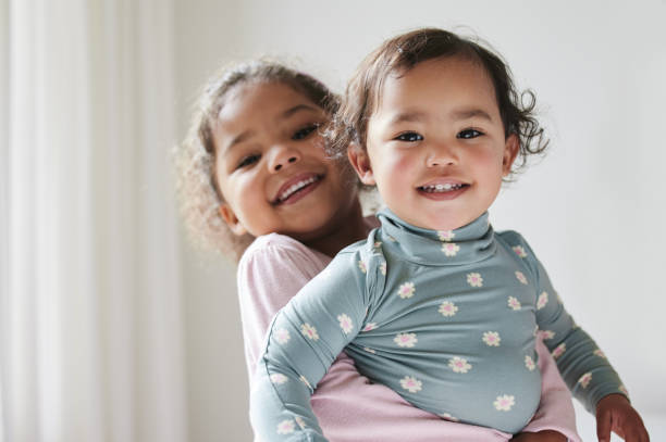 aufnahme von zwei kleinen schwestern, die zeit zu hause verbringen - baby or kind stock-fotos und bilder