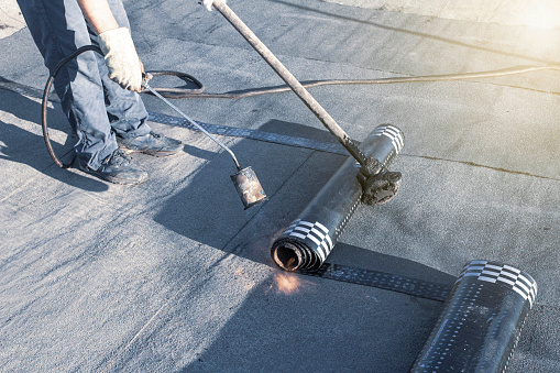 spring repair of a soft roof with rolled materials using a gas burner, the front and background are blurred with a bokeh effect