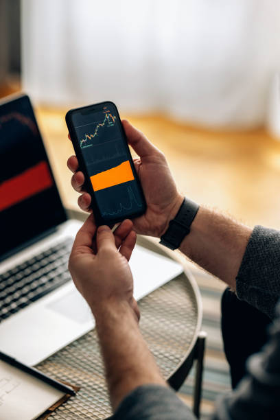 istock Work At Home: Anonymous Businessman With a Smartphone And Laptop Trading (Copy Space) 1377636675