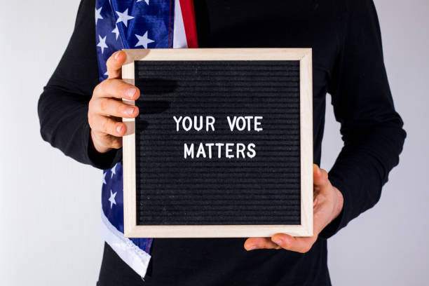 istock man with American flag holding letter board with text Your Vote Matters on white background 1377643763
