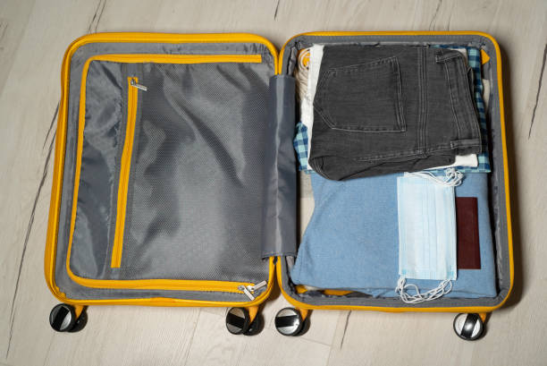 istock Packing suitcase. Yellow plastic travel bag. Clothes for a trip 1377666012