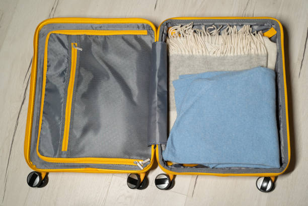 istock Packing suitcase. Yellow plastic travel bag. Clothes for a trip 1377667130