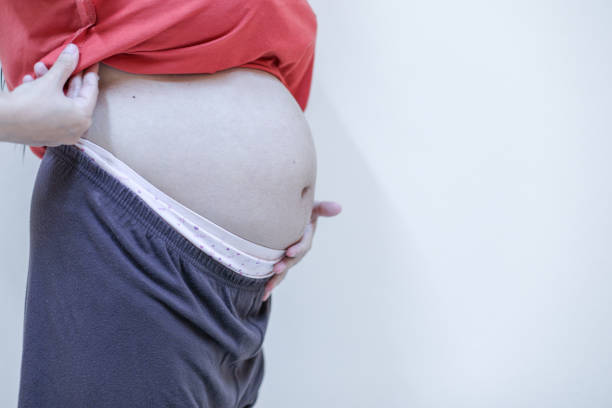 Pregnant woman future mother lying on couch relaxing, touching tender her naked belly. Pregnancy, motherhood and baby anticipation concept.
