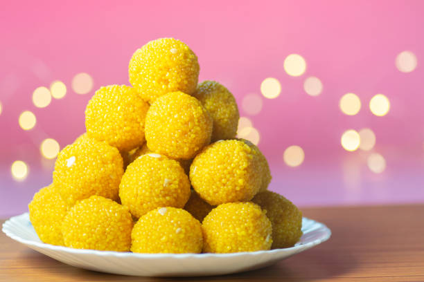 laddu doce empilhado em placa de cerâmica branca com fundo rosa e bokeh amarelo. bundi laddu fez durante muitos festivais na índia especialmente em festivais hindus e também durante a cerimônia de casamento. - specially - fotografias e filmes do acervo