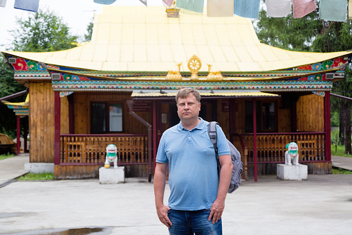 An adult tall male blond tourist near the Buddhist temple of datsan.