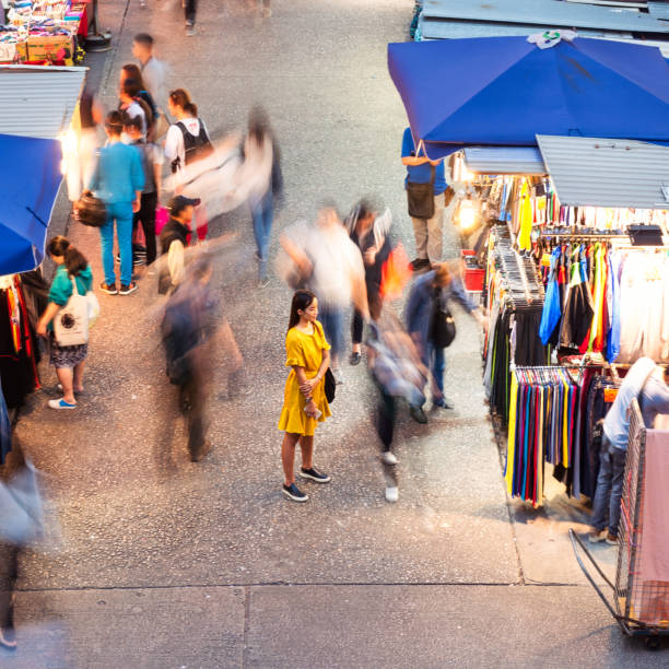 Mindfulness in the city A woman standing still and peaceful as people move around her on the street in Hong Kong. slow walk stock pictures, royalty-free photos & images