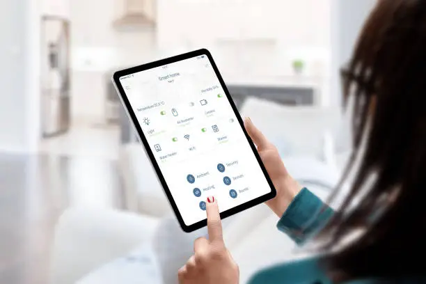 Photo of Woman use smart home automatization app for monitoring and control home devices concept