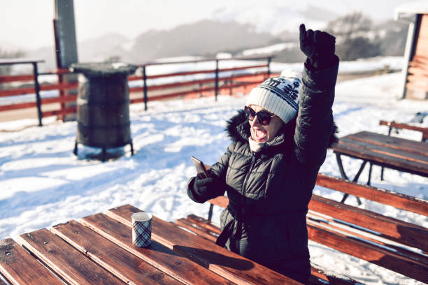 Smiling Female Online Shopping On Smartphone While Relaxing With Tea Outside On Mountain Resort
