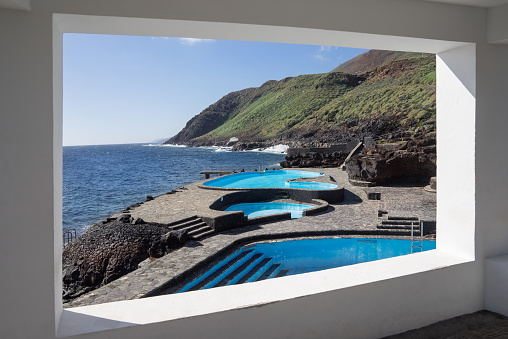 La Caleta, El Hierro, Canary Islands - view through a window opening towards the pools of the public, free swimming pool on the coast
