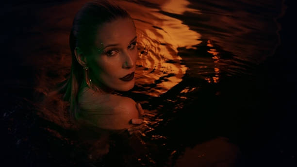 istock Underwater meditation. Seductive woman emerging from dark, gold colored water 1377752973