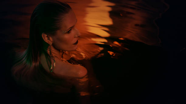istock Underwater meditation. Seductive woman emerging from dark, gold colored water 1377752979