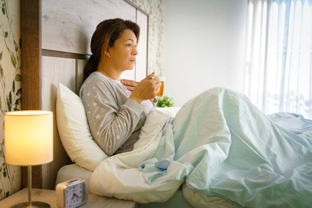 istock Woman in pajamas sitting on bed with a hot tea cup 1377820607