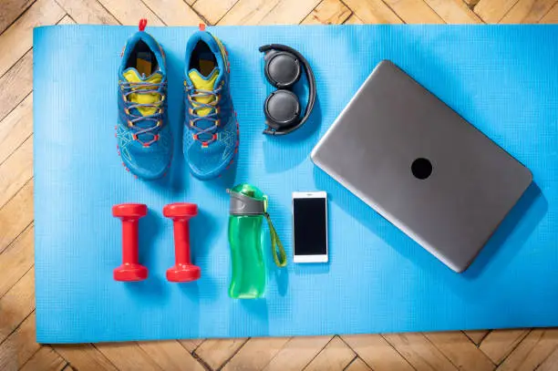 Sports shoes and fitness equipment. Fitness equipment and a laptop. Fitness at home.