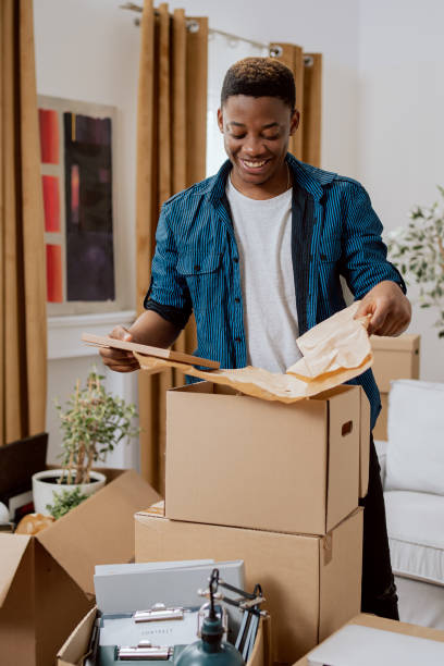 istock Unpacking cardboard boxes after moving, man cleans new apartment cluttered with items from previous home, looks at items, recalls childhood looking at picture in frame 1377841228