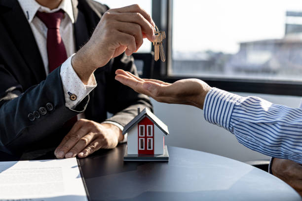 A home rental company employee is handing the house keys to a customer who has agreed to sign a rental contract, explaining the details and terms of the rental. Home and real estate rental ideas. un empleado de una empresa de alquiler de viviendas está entregando las llaves de la casa a un cliente que ha aceptado firmar un contrato de alquiler, explicando los detalles y los términos del alquiler. ideas de alquiler de viviendas e inmuebles.