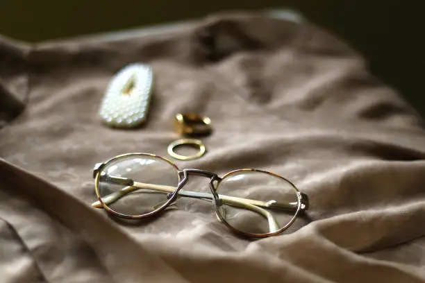 Brown vintage blouse, retro eyeglasses, pearl hair clip and gold rings. Selective focus.