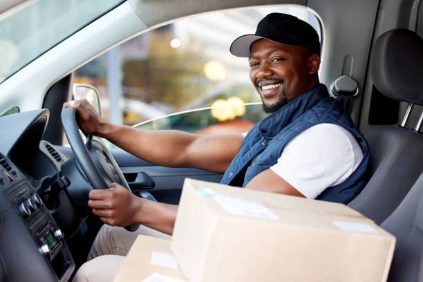 shot of young man delivering a package while sitting in a vehicle - transportation freight transportation messenger delivering imagens e fotografias de stock
