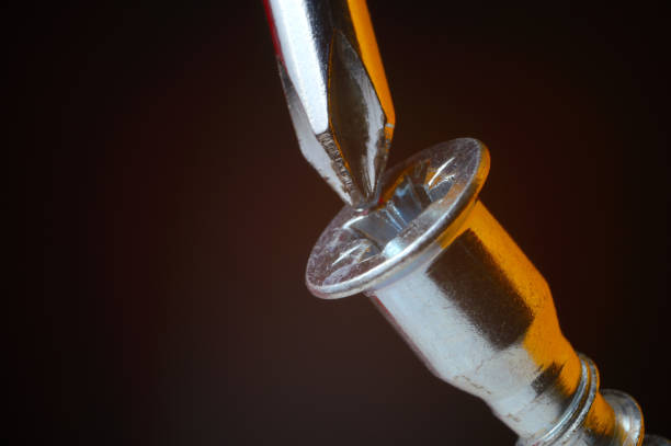 istock chrome screwdriver twists or unscrews the yellow self-tapping screw. close-up. 1377903985