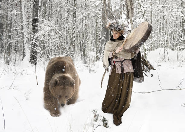 Shaman woman playing on shaman frame drum in a winter forest stock photo