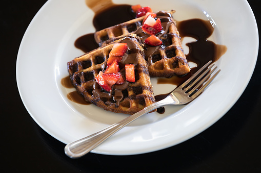 Waffles with chocolate syrup and strawberries, close up photo
