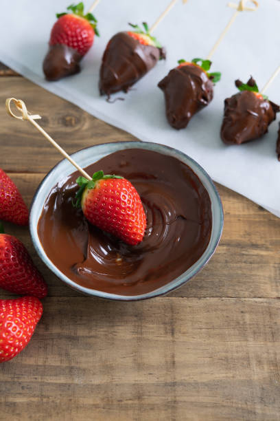 istock Strawberries with chocolate. Strawberries dipping process in chocolate. Copy space. Vertical photo. 1377947077