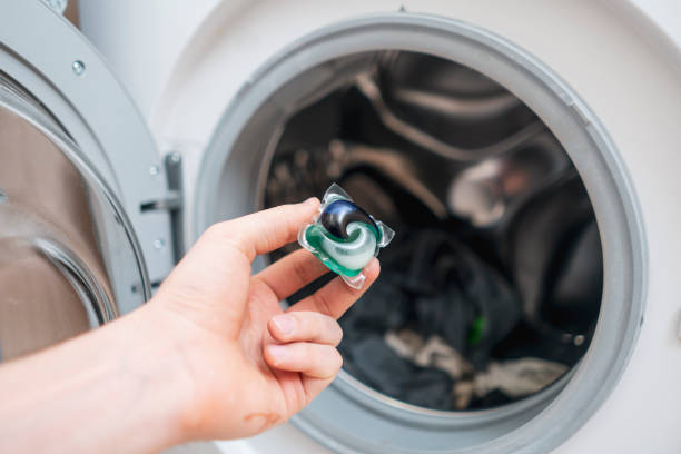 istock hand puts laundry powder capsule in washing machine with colorful clothes 1377948268