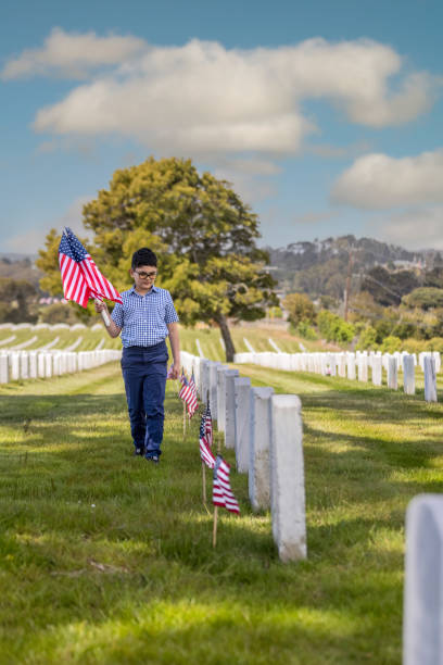 istock Young Boy Placing Flags on Veterans Grave 1377966415