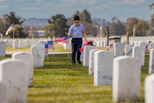 High quality stock photos of a young boy placing American flags on veterans graves at a veterans cemetery on Memorial Day.