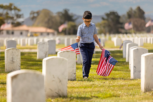 Niño colocando banderas en la tumba de los veteranos photo
