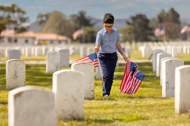 Young Boy Placing Flags on Veterans Grave stock photo
