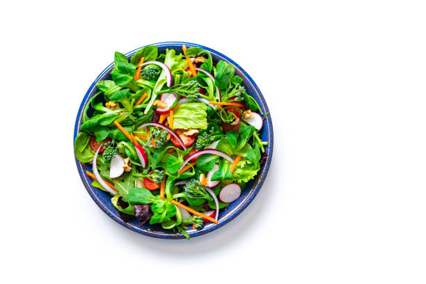 Healthy fresh green salad plate shot from above on white background Overhead view of a healthy salad plate shot on white background. The composition is at the left of an horizontal frame leaving useful copy space for text and/or logo at the right. High resolution 42Mp studio digital capture taken with SONY A7rII and Zeiss Batis 40mm F2.0 CF lens directly above stock pictures, royalty-free photos & images