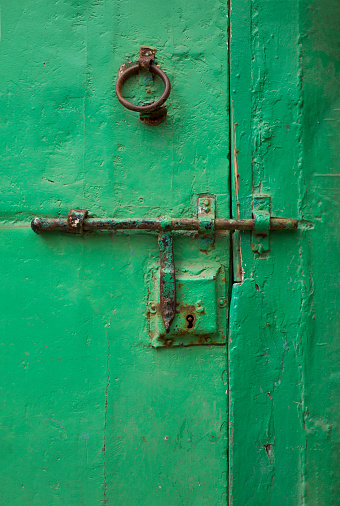 Closeup and detail of old, weathered door painted bright green in Essaouira, Morocco