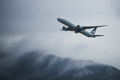 Hong Kong - 5 September 2019: A Cathay Pacific Boeing B777-300ER (B77W) taking off from Hong Kong International Airport against the backdrop of the mist covered mountains of Lantau Island.
