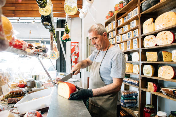 cheesemonger bedient kundenbestellungen - feinkostgeschäft stock-fotos und bilder