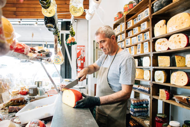 Cheesemonger serving customer orders Delicatessen Store owner serving customer orders delicatessen stock pictures, royalty-free photos & images