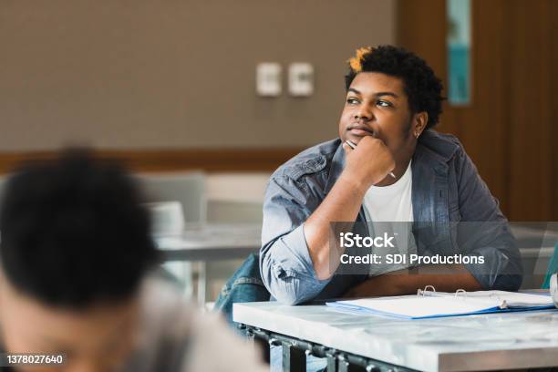 Teen Boy Rests Chin On Hand And Daydreams In Class Stock Photo - Download Image Now - Boredom, Teenager, School Building