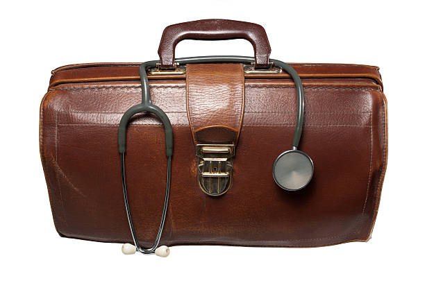 A doctors brown bag with a stethoscope in top Brown leather much used doctor's bag with hung stethoscope. Every physician's accessory. Isolated on white. leather medical bag stock pictures, royalty-free photos & images