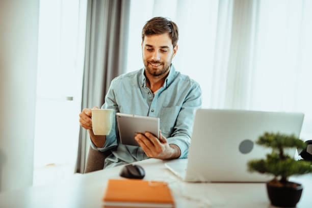 istock Man using laptop and digital tablet for business at home 1378076330