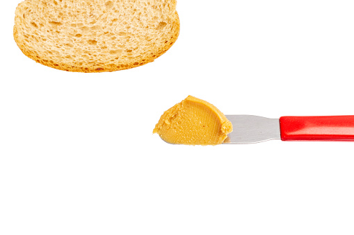 Knife with peanut butter and a slice of bread on a white background with copy space