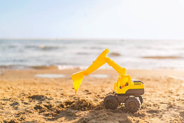 Toy excavator on the beach with copy space.