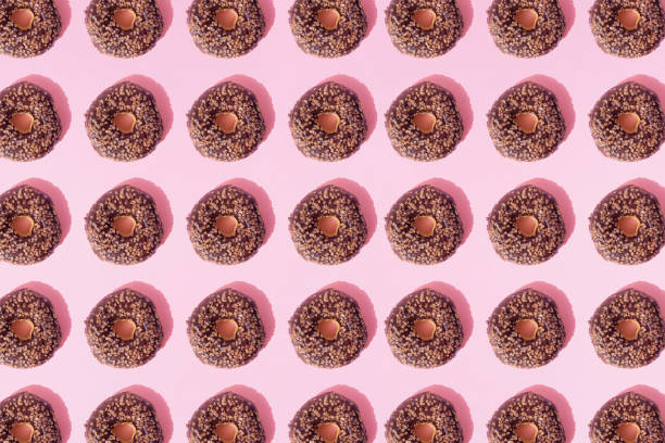 istock Arranged ring donuts with chocolate glaze and small crumbs on a pink pastel background. Minimal design. 1378088191