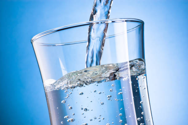 istock Water pouring into glass on blue background 1378091405