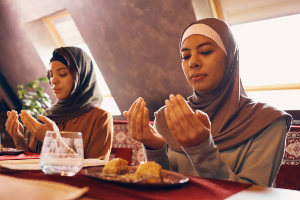 istock Young Muslim women praying while having dessert at home. 1378098872