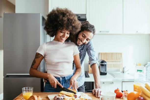 Multiracial family in kitchen expressing love and happiness Multiracial heterosexual couple in kitchen, preparing French food young couple stock pictures, royalty-free photos & images