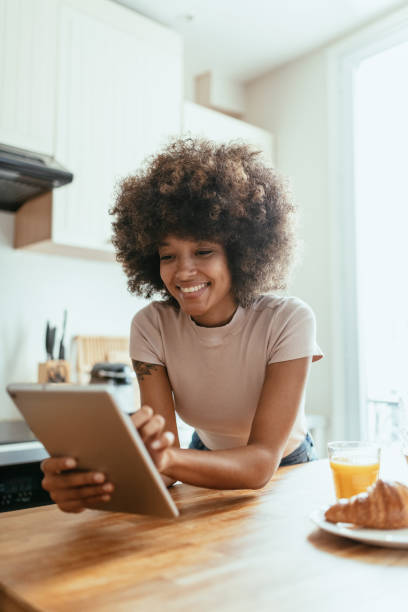 African American woman working from home and drinking coffee stock photo