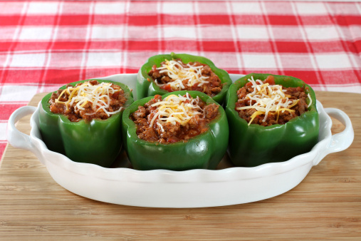 Fresh stuffed peppers in an oval baking dish.